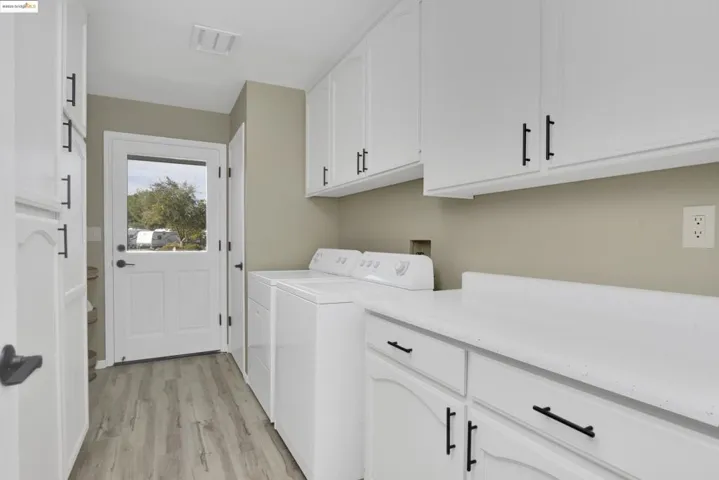 Laundry room featuring light wood-type flooring, independent washer and dryer, and cabinet space
