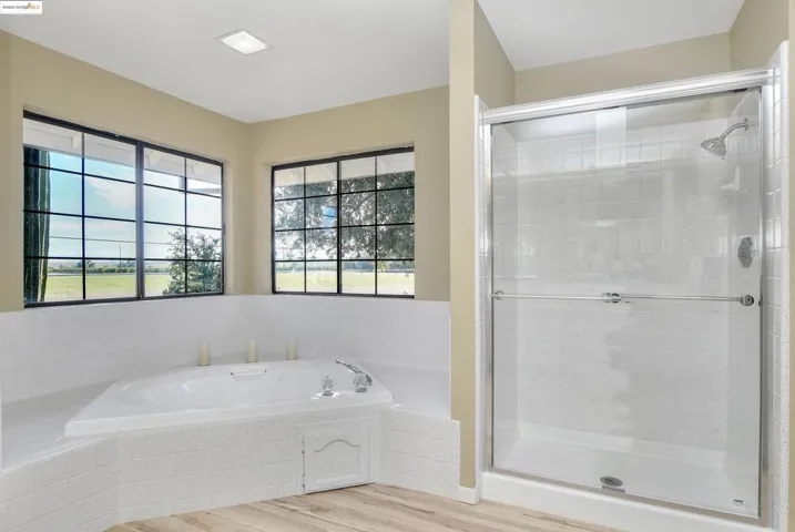 Full bath with light wood-style flooring, a bath, and a stall shower
