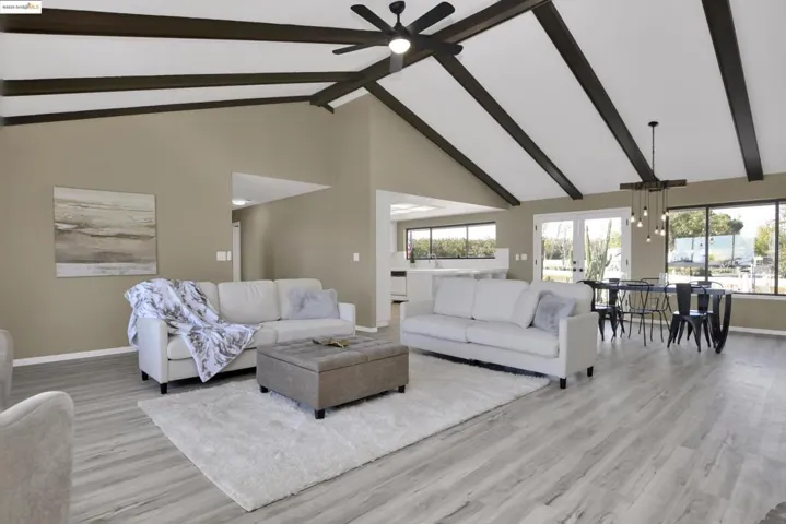 Living area with high vaulted ceiling, beamed ceiling, light wood-style flooring, and a ceiling fan