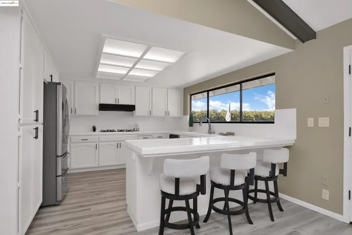 Kitchen with decorative backsplash, a peninsula, white cabinets, a breakfast bar area, and light wood finished floors