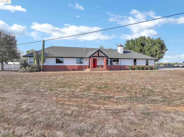 Single story home with a chimney, brick siding, and roof with shingles