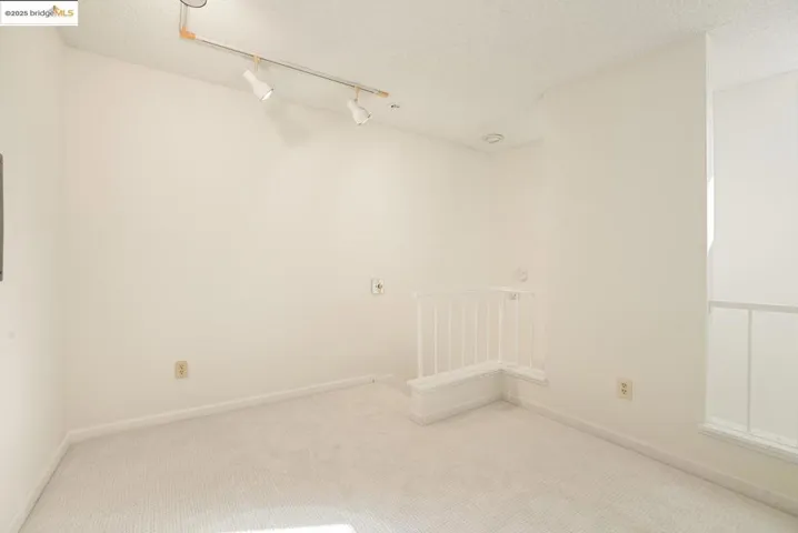 Carpeted empty room featuring a textured ceiling and rail lighting