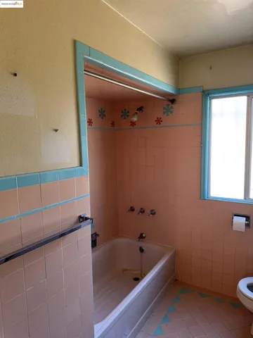 Bathroom featuring light tile patterned flooring, shower / washtub combination, and tile walls