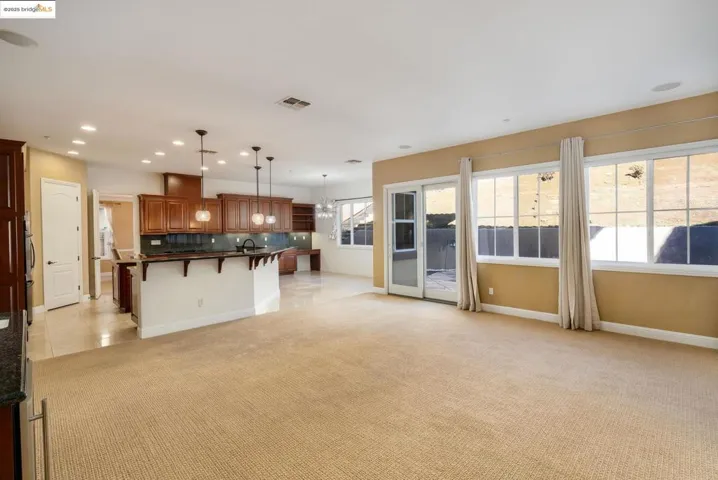 Kitchen with dark countertops, a kitchen breakfast bar, decorative backsplash, open floor plan, and light carpet
