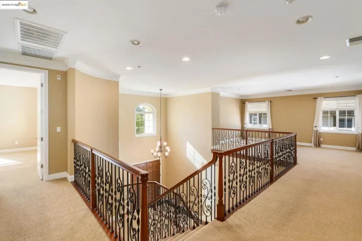 Hall with carpet flooring, a chandelier, ornamental molding, recessed lighting, and an upstairs landing