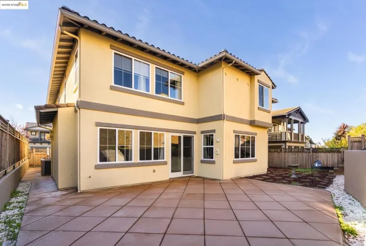 Rear view of house with a fenced backyard, stucco siding, and a patio area