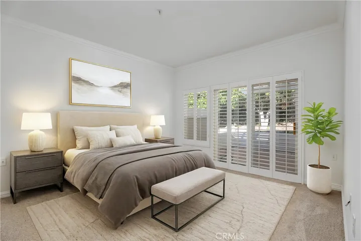 The large primary bedroom with plantation shutters and a sliding glass door out to the substantial patio.  (Virtually staged)