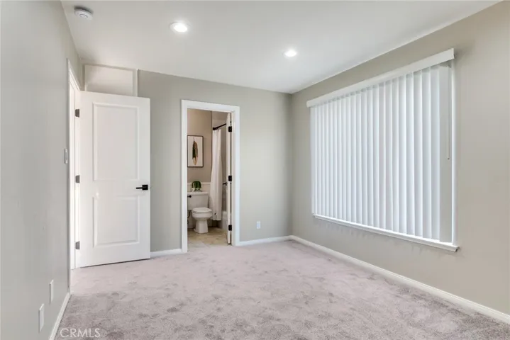 Main bedroom with new carpet and new closet doors, offering added storage behind the entry door and direct access to the en suite full bath through updated doors.
