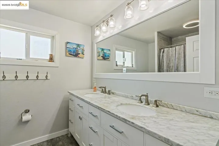 Bathroom featuring double vanity, curtained shower, and dark wood-style flooring