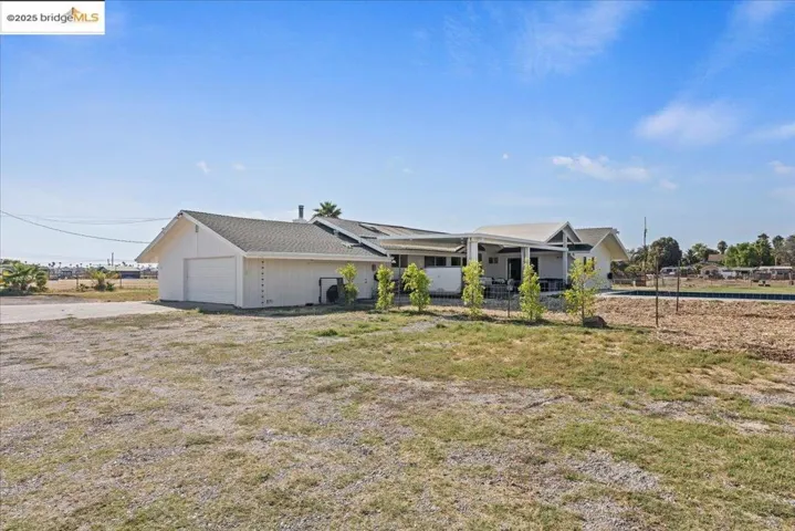 View of front facade with a garage, roof mounted solar panels, and driveway