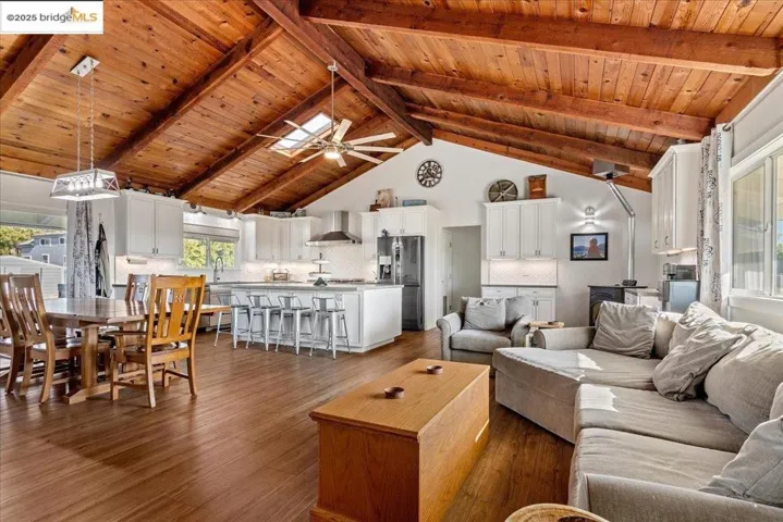 Living room with high vaulted ceiling, dark wood-style floors, a wood ceiling with exposed beams, and a ceiling fan