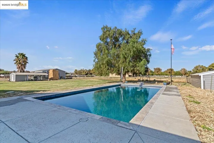 Swimming pool featuring a lawn, a diving board, and a patio