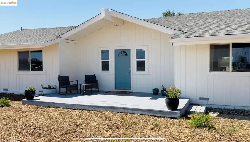 Doorway to property featuring a shingled roof, a deck, and crawl space