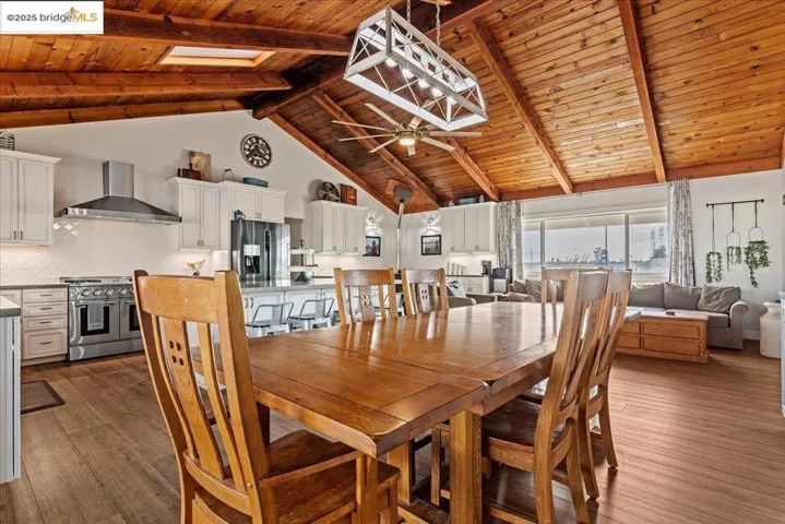 Dining space featuring a wooden ceiling with exposed beams, high vaulted ceiling, dark wood-type flooring, and ceiling fan