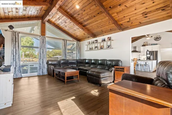 Living area with wood finished floors, a wood ceiling with exposed beams, and high vaulted ceiling