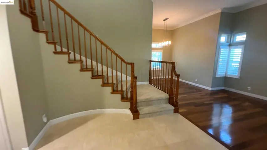 Stairs with ornamental molding, a chandelier, a towering ceiling, and tile patterned floors