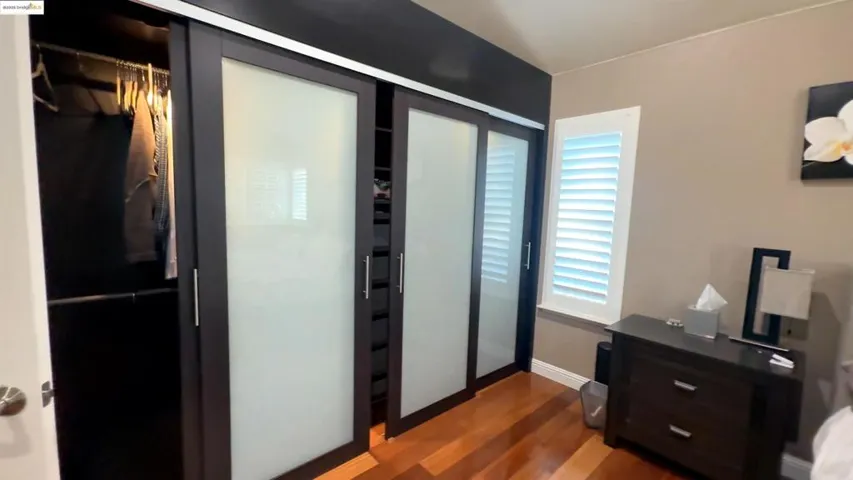 Bedroom with dark wood-style flooring and a closet