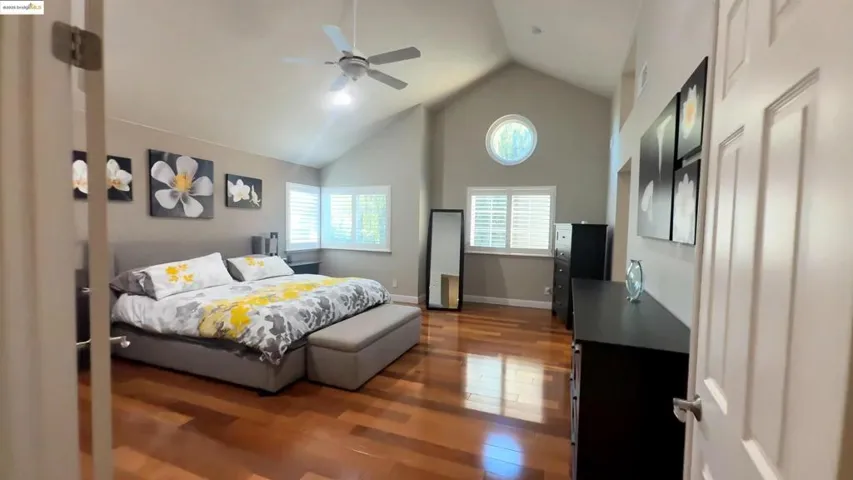 Bedroom featuring dark wood-style floors, high vaulted ceiling, and ceiling fan