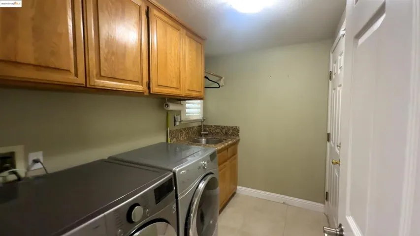 Washroom featuring cabinet space, washing machine and dryer, and light tile patterned flooring
