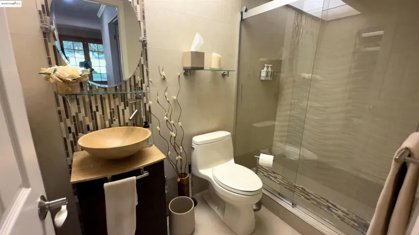 Bathroom with tile walls, decorative backsplash, vanity, and a shower stall