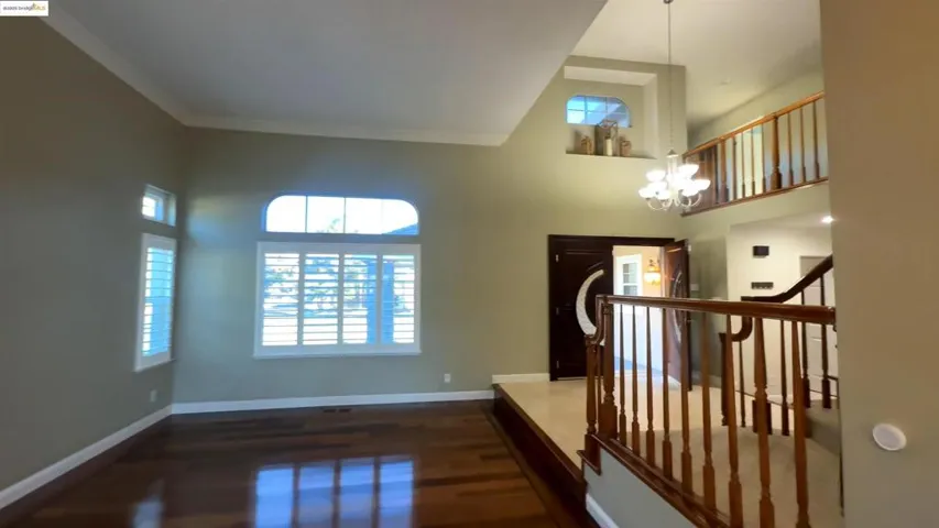 Foyer entrance with a chandelier, dark wood-style flooring, plenty of natural light, a high ceiling, and ornamental molding