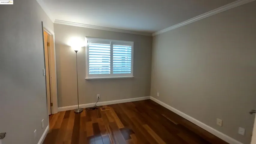 Unfurnished bedroom with dark wood-style flooring and ornamental molding