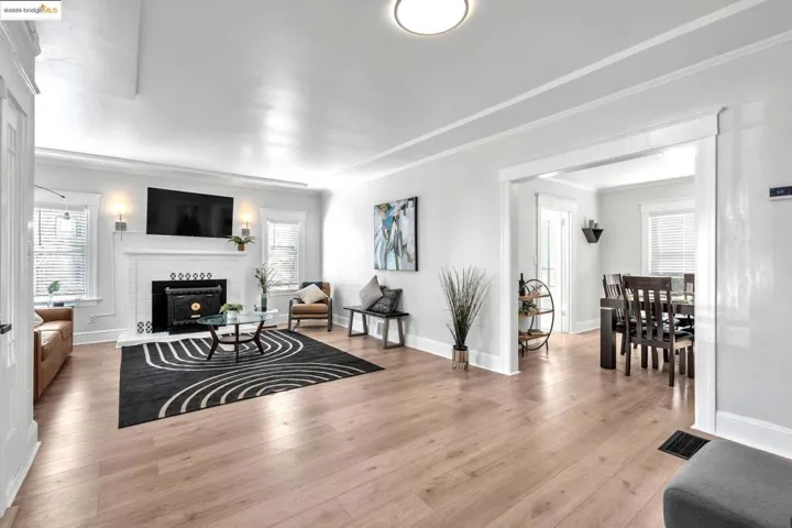 Living room featuring light wood finished floors, healthy amount of natural light, a fireplace, and crown molding