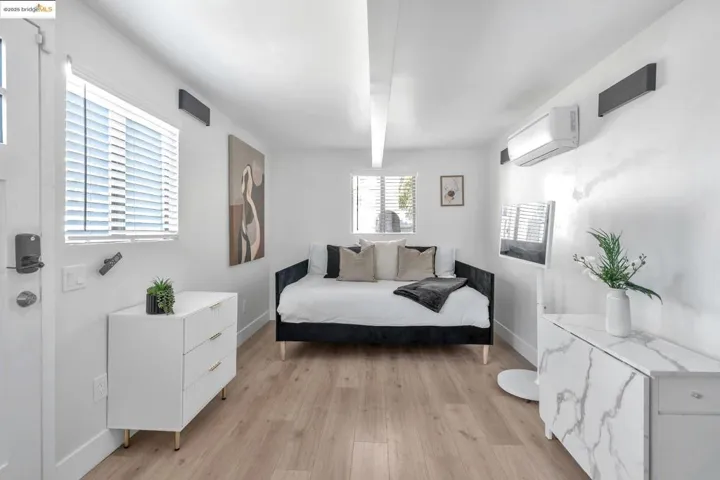 Bedroom with light wood-type flooring and an AC wall unit