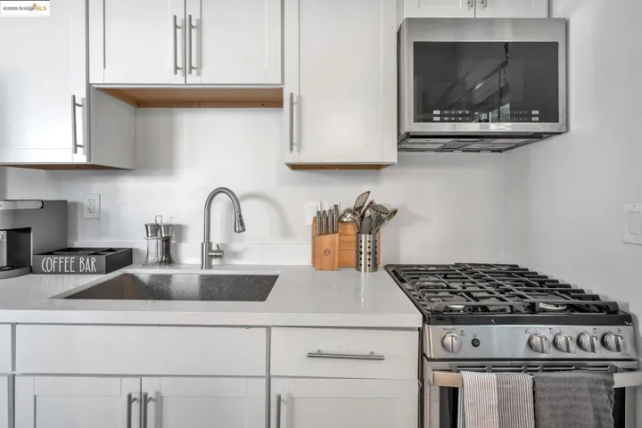 Kitchen with appliances with stainless steel finishes, white cabinets, and light stone counters