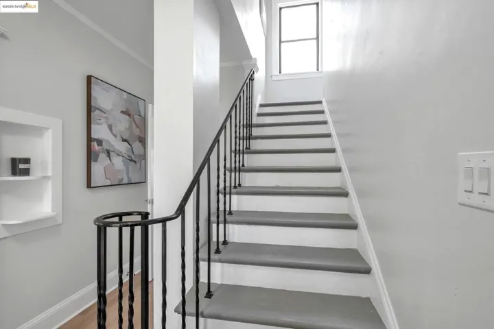Stairway with crown molding and wood finished floors