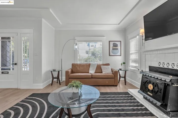 Living area with light wood finished floors, crown molding, and a tiled fireplace