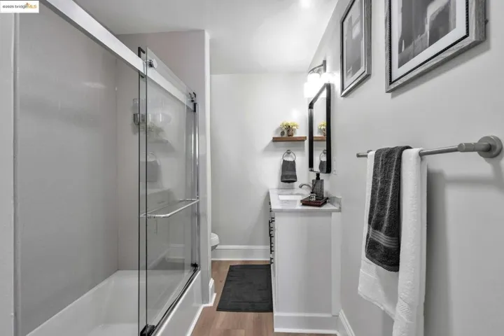 Full bathroom featuring vanity, a shower with door, and light wood-style floors