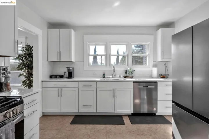 Kitchen with appliances with stainless steel finishes, white cabinetry, backsplash, and healthy amount of natural light
