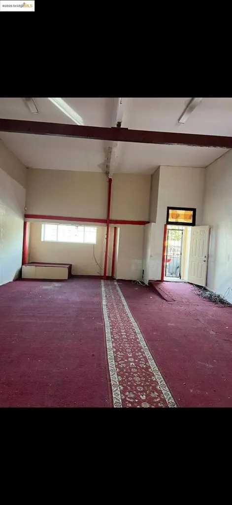 Unfurnished room featuring carpet, beamed ceiling, and plenty of natural light