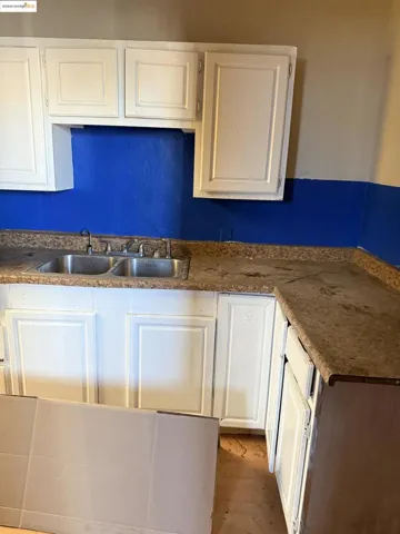 Kitchen featuring white cabinetry, dark countertops, and wood finished floors