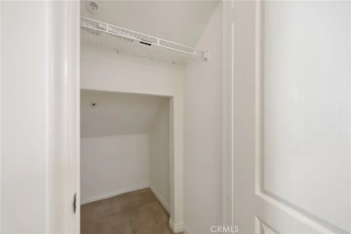 A very spacious hall closet with room for storage under the staircase, as well as a coat hanging bar.