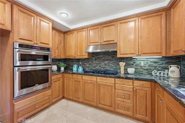 A very spacious kitchen with granite countertops, a window is located over the large stainless steel sink and at eat at counter is just out of the view.
