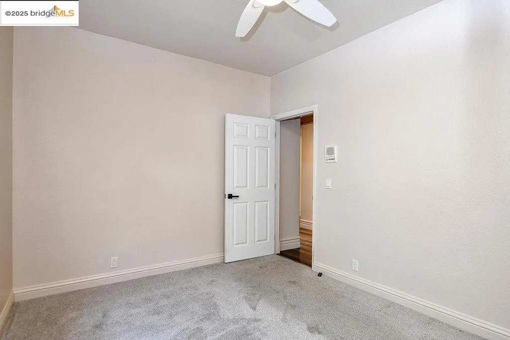 Carpeted empty room featuring baseboards and a ceiling fan
