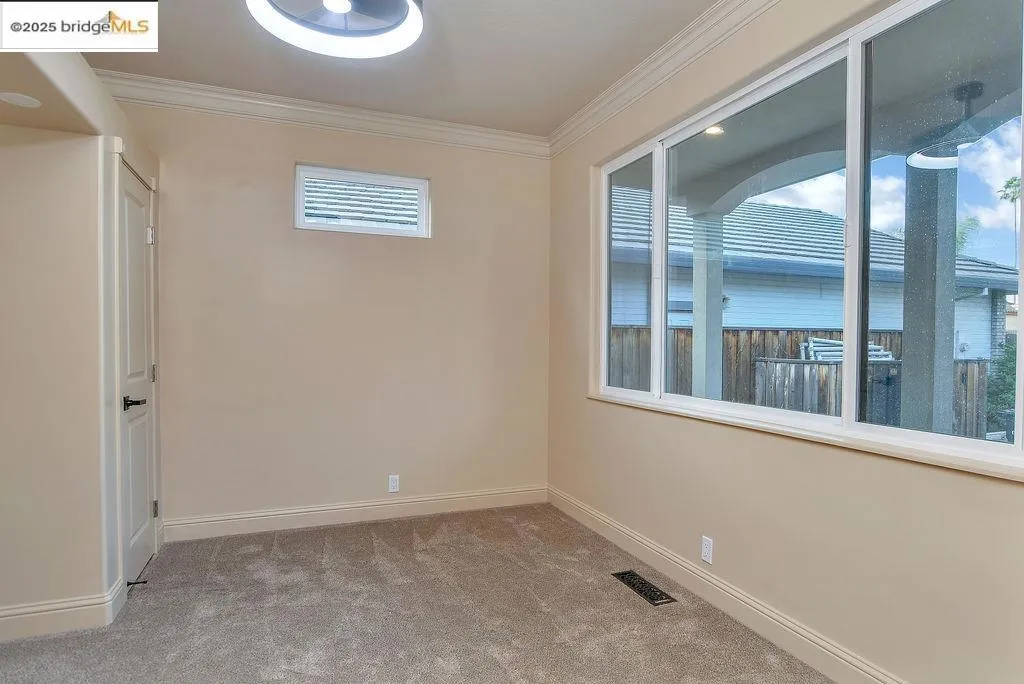 Empty room featuring ornamental molding and light colored carpet