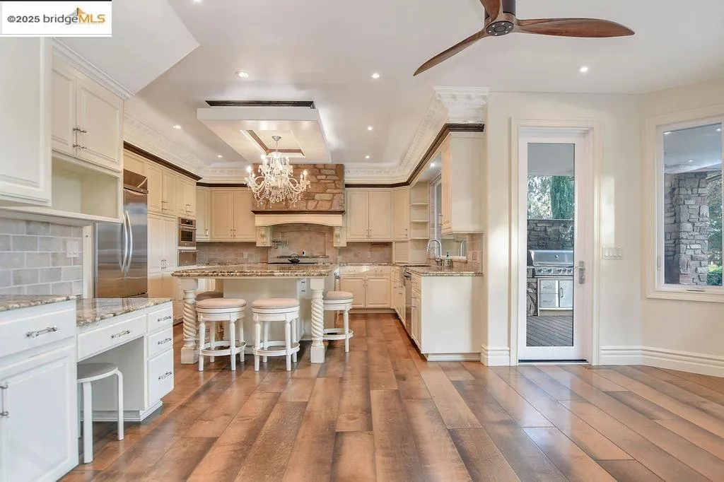 Kitchen featuring a breakfast bar area, light stone countertops, a chandelier, tasteful backsplash, and dark wood finished floors