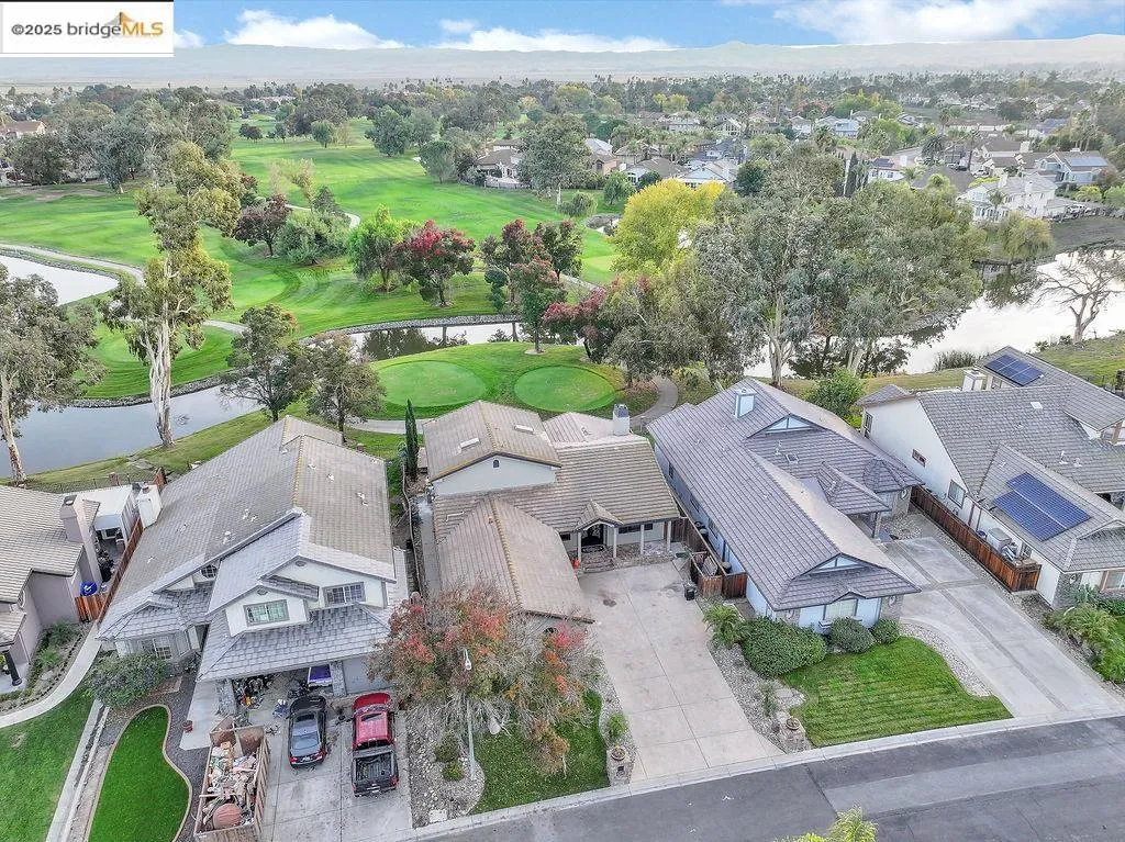 Aerial perspective of suburban area featuring a golf course and a nearby body of water