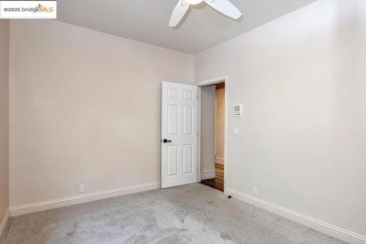 Carpeted empty room featuring baseboards and a ceiling fan
