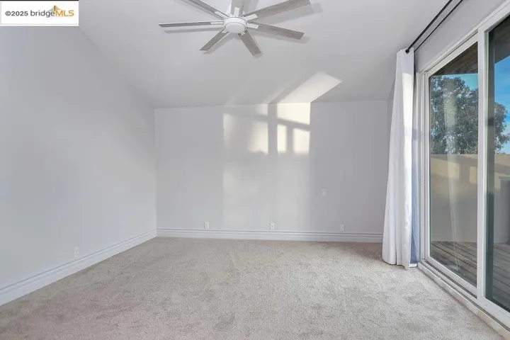 Empty room with carpet flooring, a ceiling fan, and vaulted ceiling
