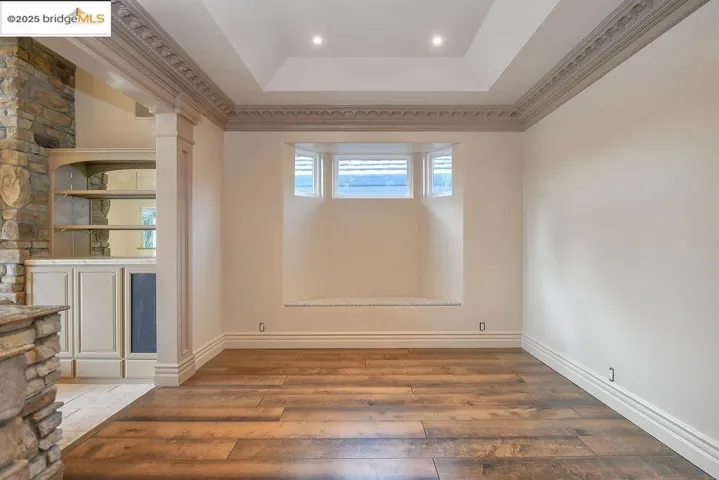 Spare room featuring hardwood / wood-style floors, a tray ceiling, and crown molding