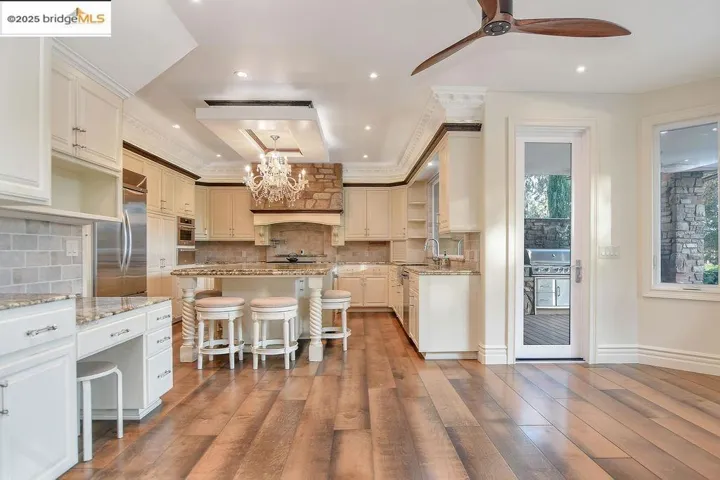Kitchen featuring a breakfast bar area, light stone countertops, a chandelier, tasteful backsplash, and dark wood finished floors