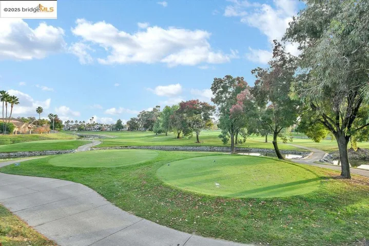 View of community featuring golf course view, an area to practice putting, and a lawn