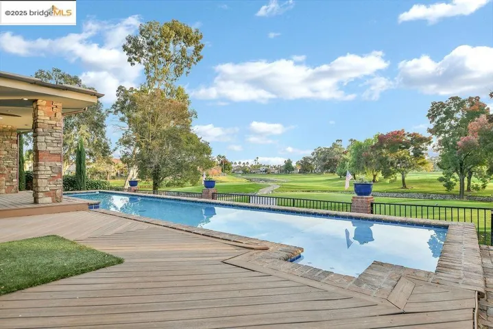 Swimming pool with a yard, view of golf course, a patio area, and a wooden deck
