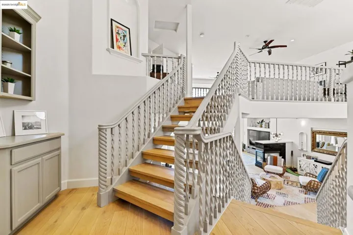 Stairway with wood finished floors, a ceiling fan, and a towering ceiling