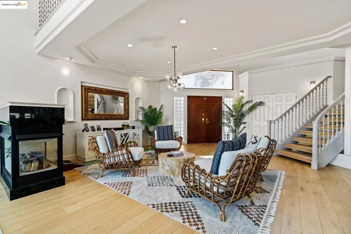 Living room featuring light wood-style flooring, a chandelier, stairway, recessed lighting, and a tiled fireplace