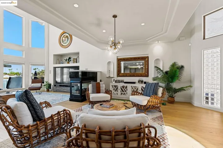 Living room with a towering ceiling, a tile fireplace, light wood-style flooring, recessed lighting, and a chandelier